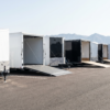 Row of new white and black enclosed V-nose cargo trailers on a dealer lot — enclosed trailers for sale at PrimeLoad