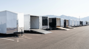 Row of new white and black enclosed V-nose cargo trailers on a dealer lot — enclosed trailers for sale at PrimeLoad