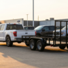 White Ford F-150 hitched to a black 6x12 tandem axle landscape utility trailer at golden hour — best utility trailer for f-150 at PrimeLoad