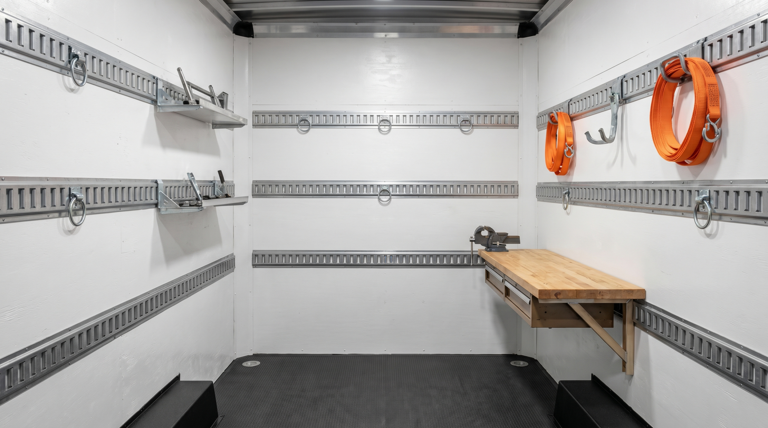 Interior of a white enclosed cargo trailer with horizontal e-track rails on side walls accepting tie-down rings, shelf brackets, and accessories — cargo trailer e-track at PrimeLoad