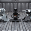 Three gooseneck hitch ball assemblies side-by-side: B&W Companion, Curt EZr, Reese ELITE in a pickup bed — gooseneck hitch comparison at PrimeLoad