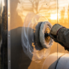 Contractor polishing the side panel of a polished aluminum enclosed trailer with a buffer — how to polish an aluminum trailer at PrimeLoad