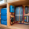 Camper trailer interior with lithium battery bank, solar charge controller, inverter, and wiring panel — boondocking battery setup at PrimeLoad